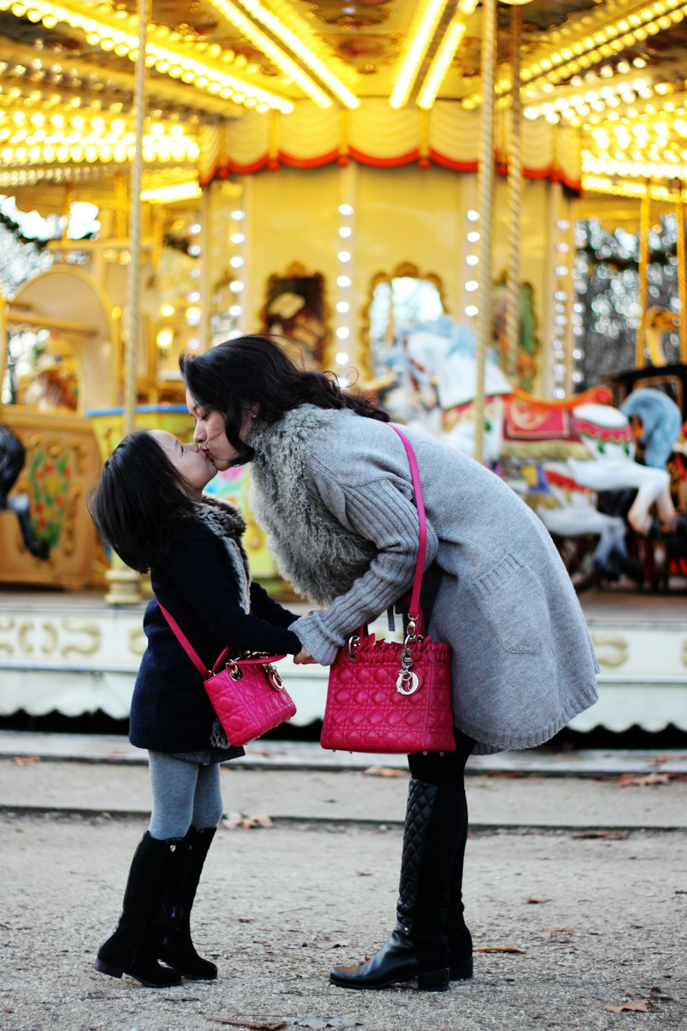 girl kiss woman wearing matching pink leather bag