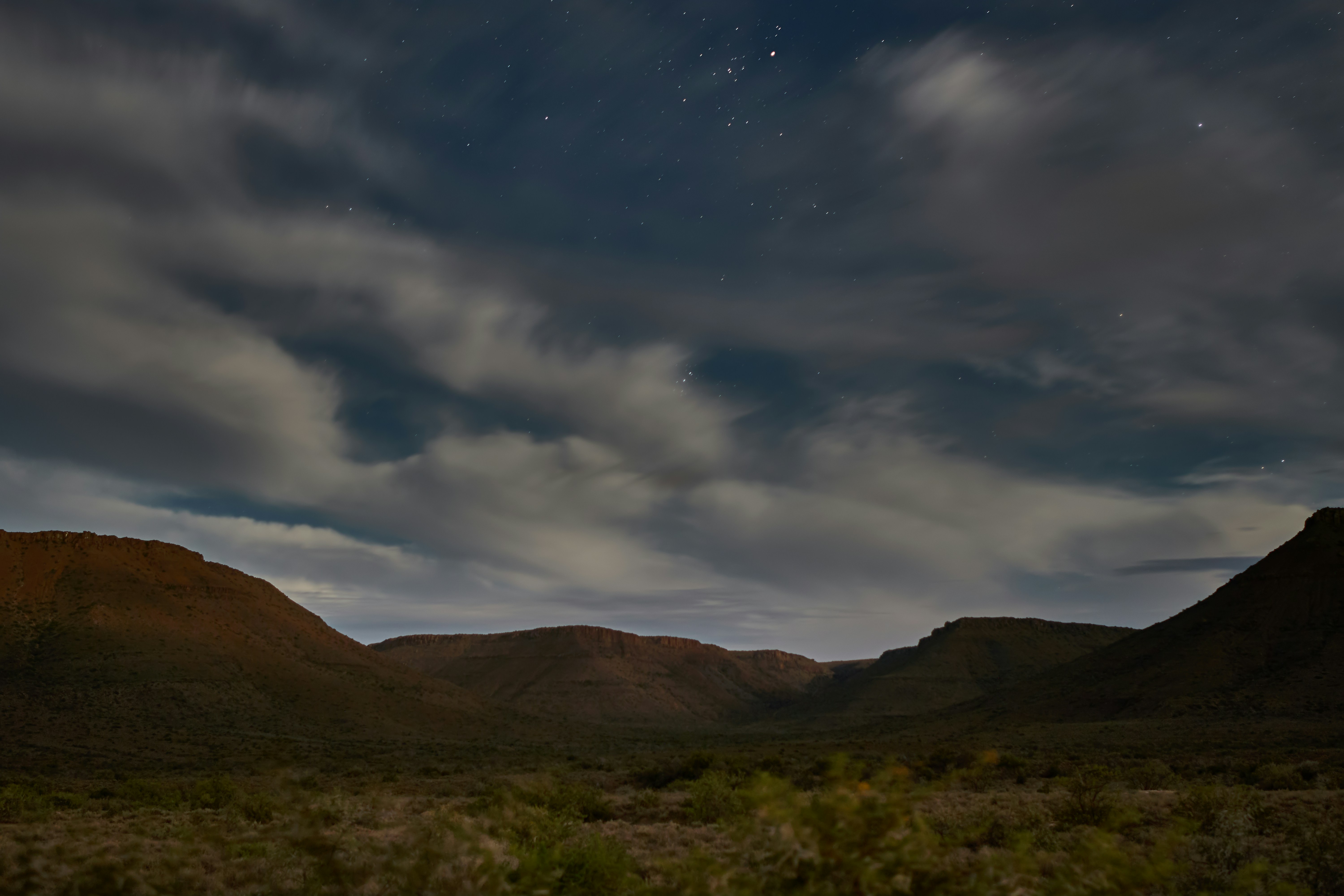 the night sky over a mountain range with stars in the sky