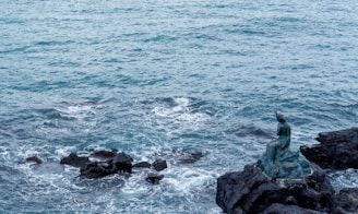 A serene mermaid lounging on a rock with cream-colored waves gently crashing around her.