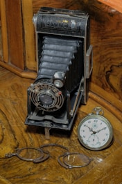A vintage stereoscopic camera displayed on a wooden table with old 3D cards scattered around.