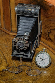 A vintage stereoscopic camera from the late 19th century displayed on a wooden table with old stereoscopic cards scattered around.
