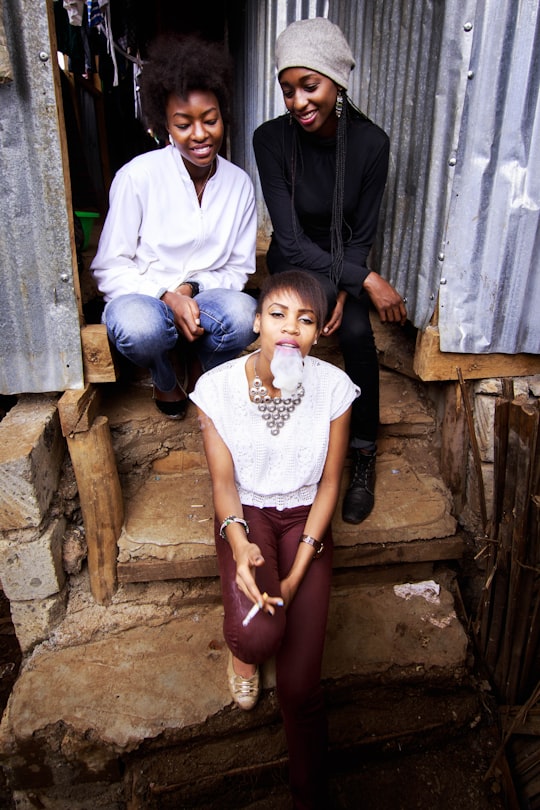 three woman sitting on stairs during daytime in Kibera Kenya