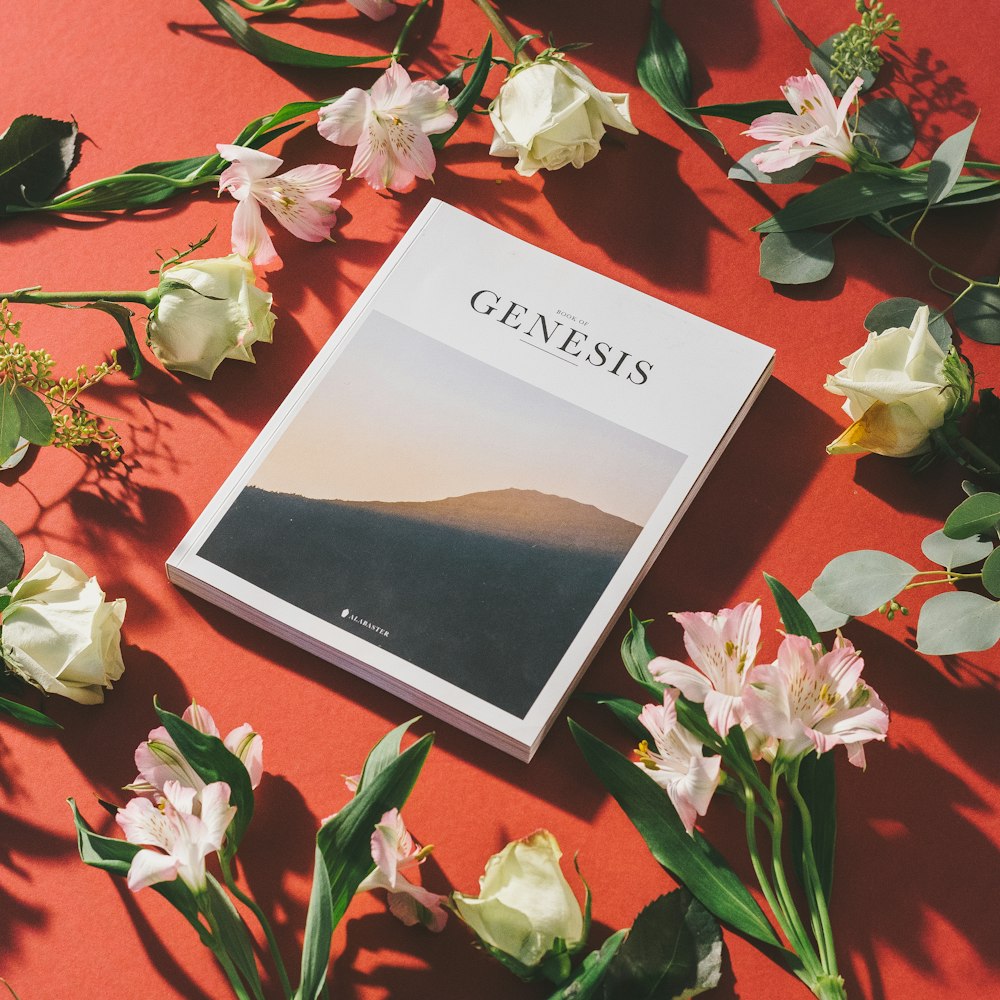 Libro impreso por el Génesis por flores sobre superficie roja