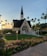 A serene sunrise over a quiet chapel surrounded by blooming spring flowers.