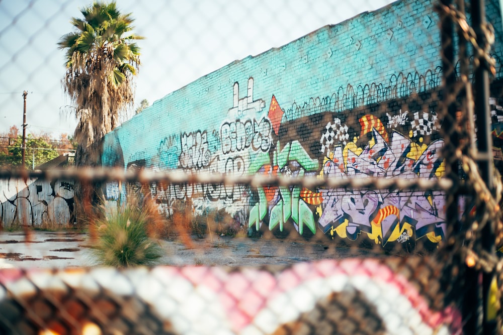 a graffiti covered wall behind a chain link fence