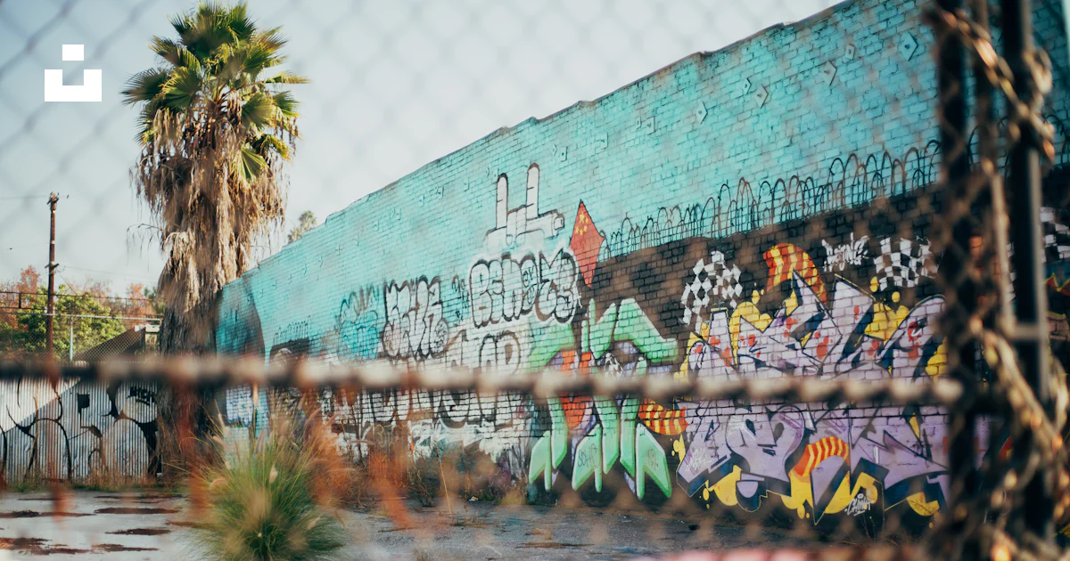 Chain Graffiti A graffiti covered wall behind a chain link fence photo – Free Los ...