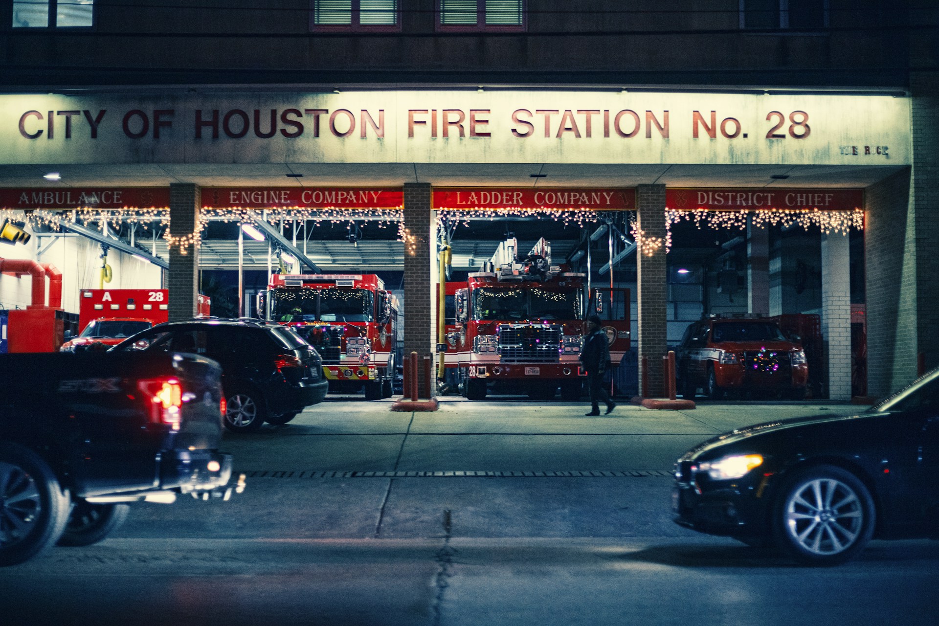 cars on road passing by City of Houston Fire Station No. 28 at nighttime