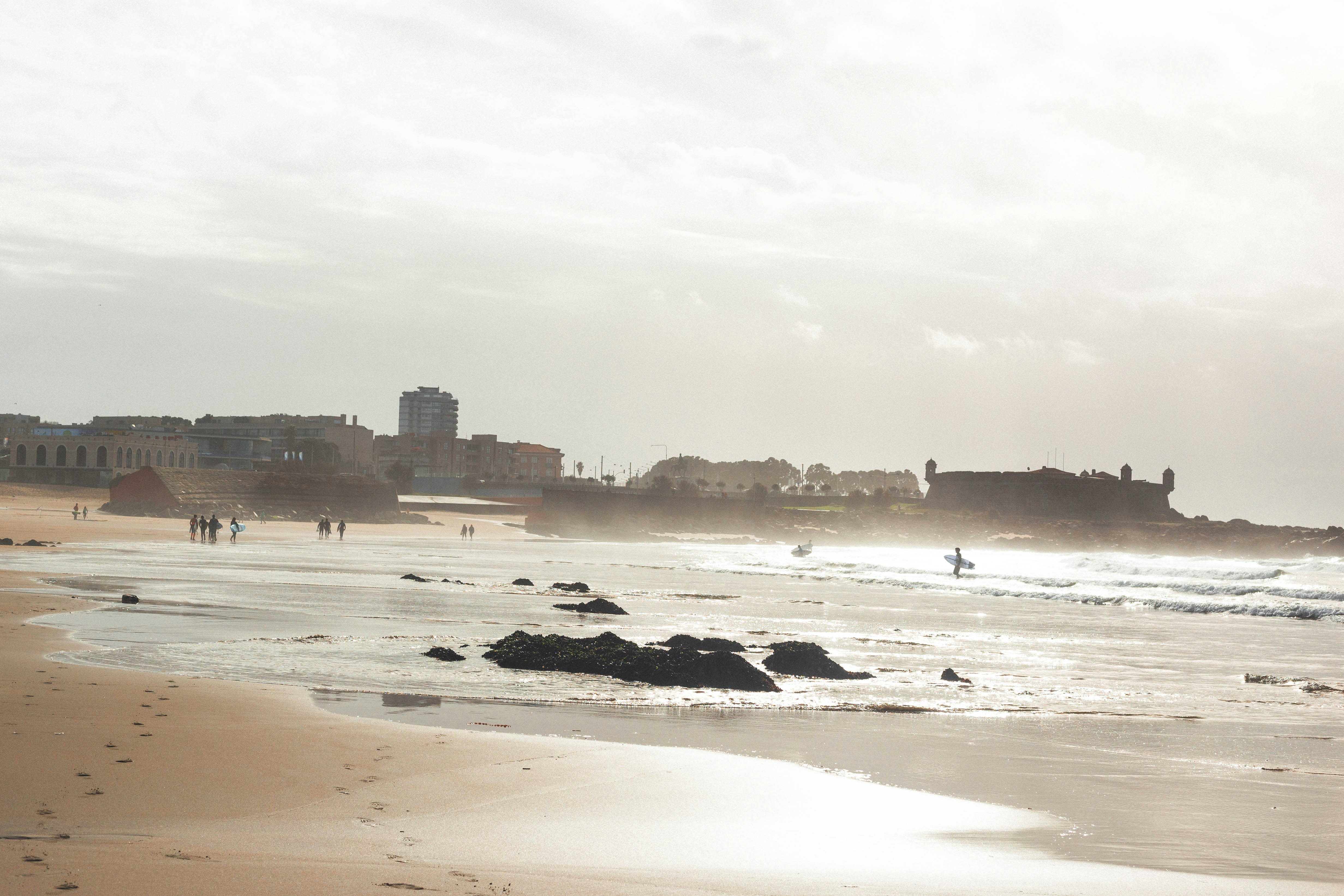 people on beach viewing hotels and buildings under white sky