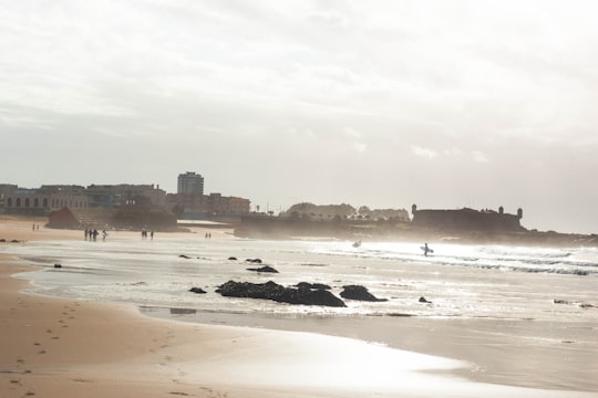 people on beach viewing hotels and buildings under white sky in Oporto Portugal