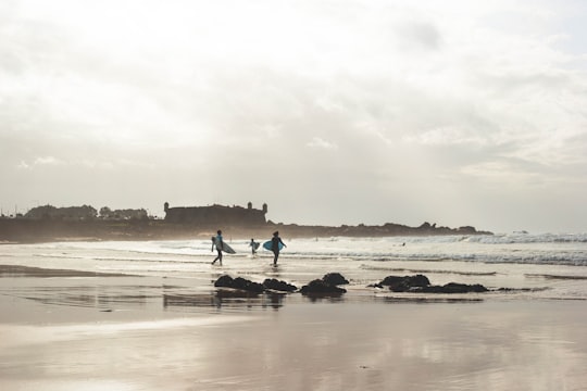 silhouette of person holding surfboard on seashore in Oporto Portugal