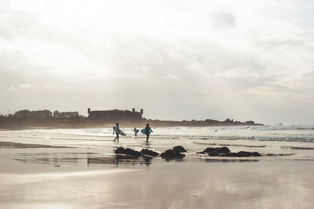 silhouette of person holding surfboard on seashore