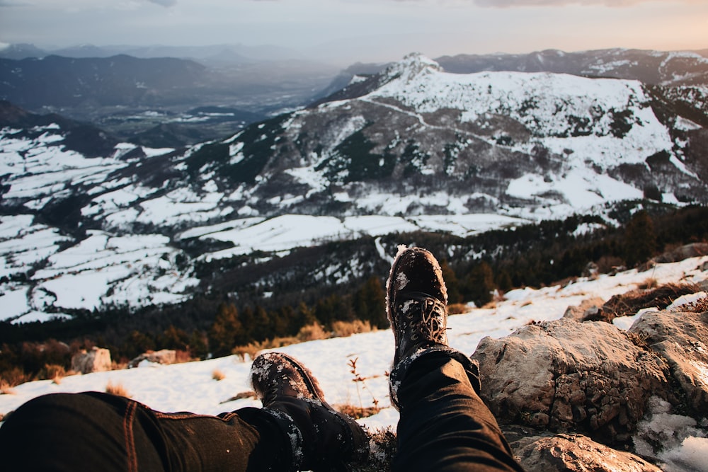 man sitting on a mountain peak overlooking mountain alps