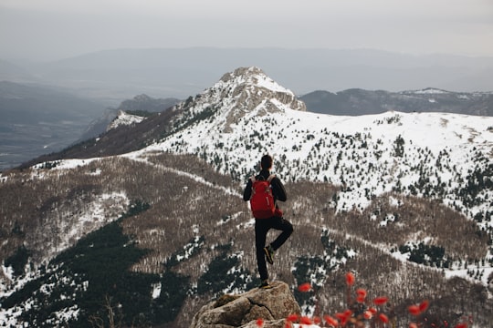 man standing on a mountain peak using one foot only in Céüse France