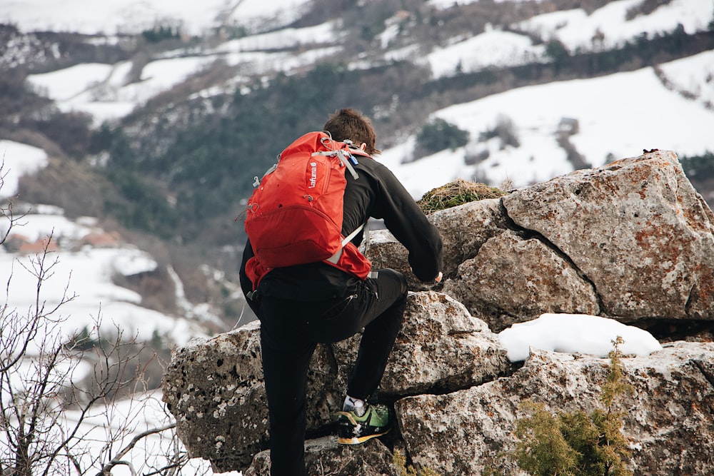 man climbing up rocks in a snowy mountain