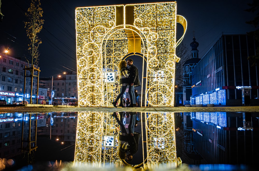 man and woman kissing near lighted tower decor during nighttime