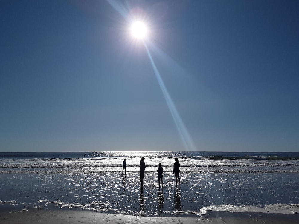 silhouette photography of four persons standing in shore during daytime