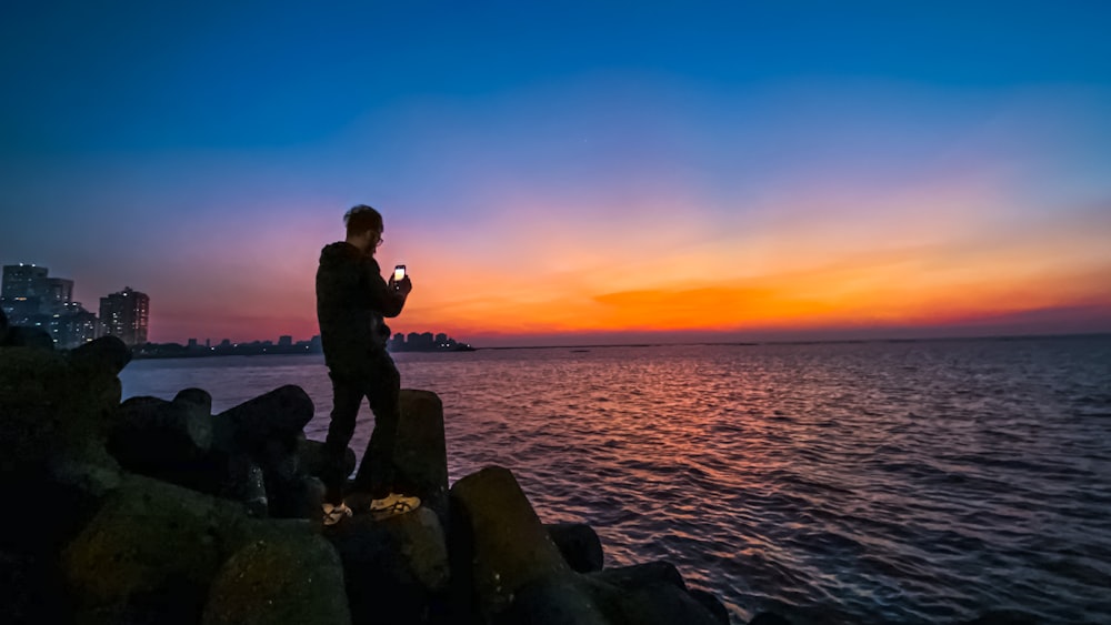 man standing on stones near body of water