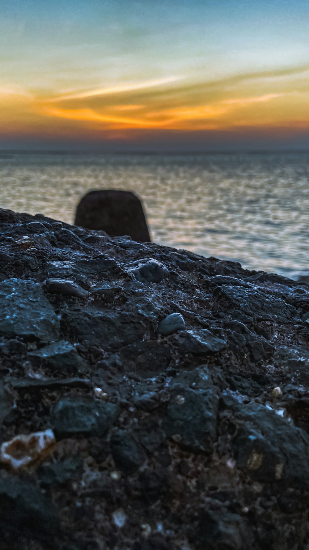 夜明けの海近くの灰色の石