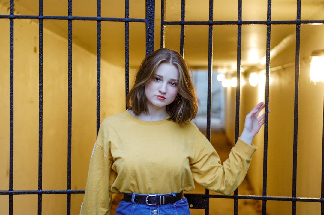 selective focus photography of woman standing beside gate