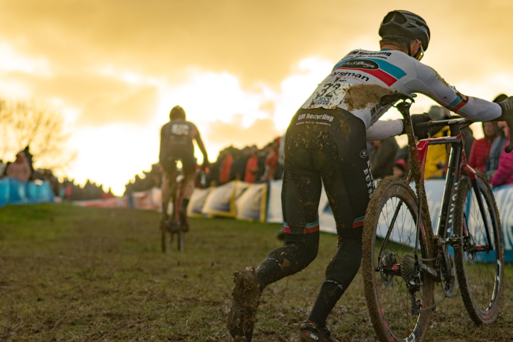 person pushing black bike with mud