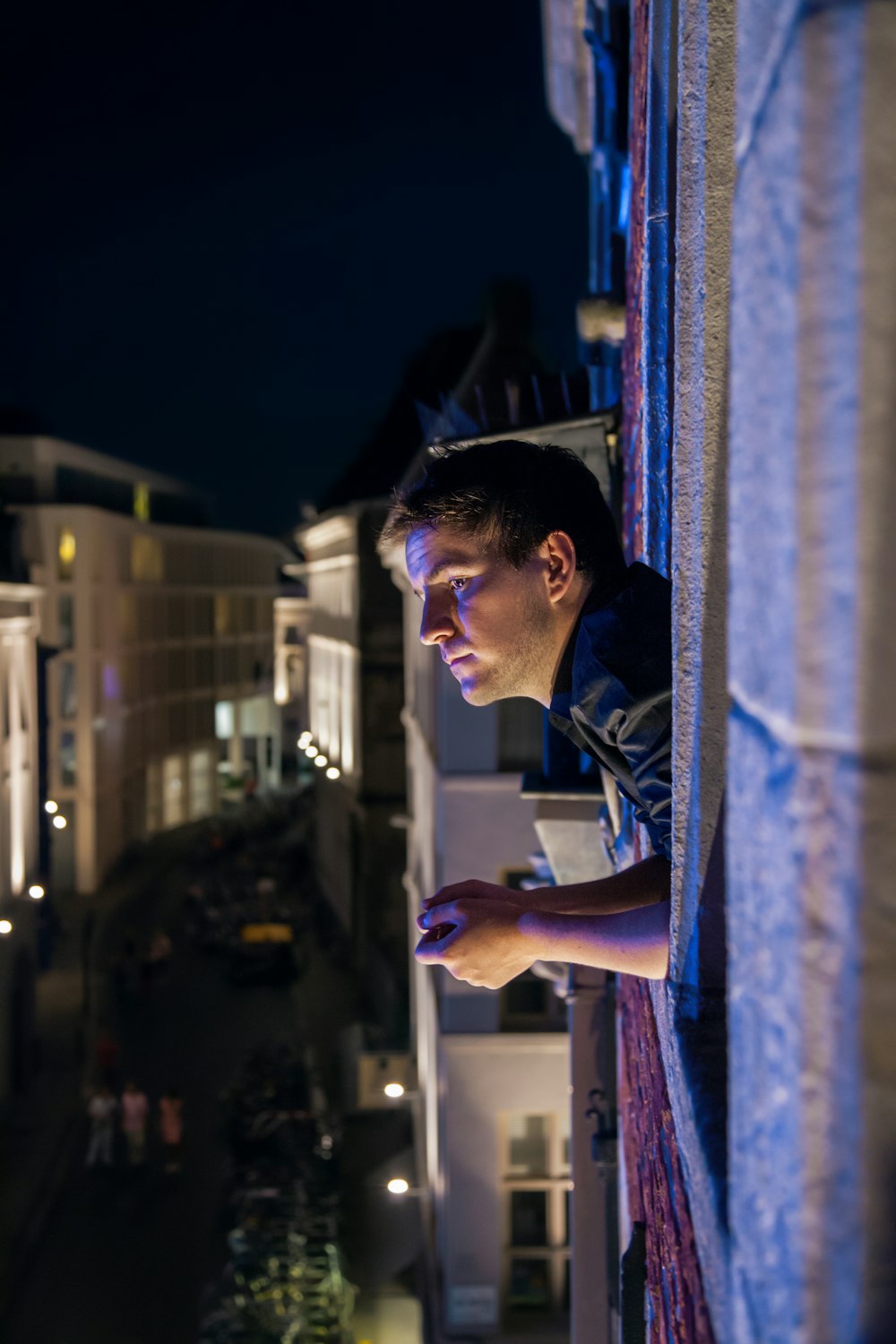 man standing on balcony and leaning on fence during nighttime