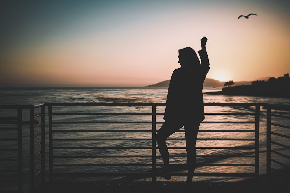 silhouette of woman standing near the fence