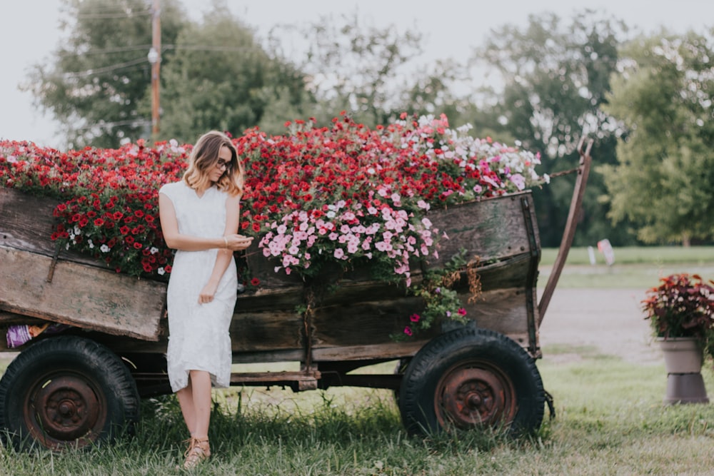 woman leaning on a wooden trailer filled with flowers