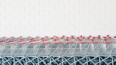 gray-and-red metal shopping cart lot beside wall