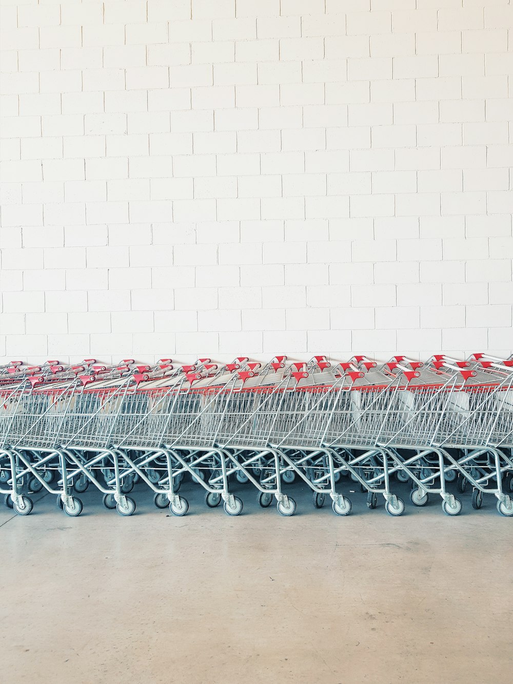 Carrello della spesa in metallo grigio e rosso a lato del muro