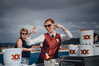 A candid moment of Baleigh serving drinks with a warm smile on a sunny yacht deck.