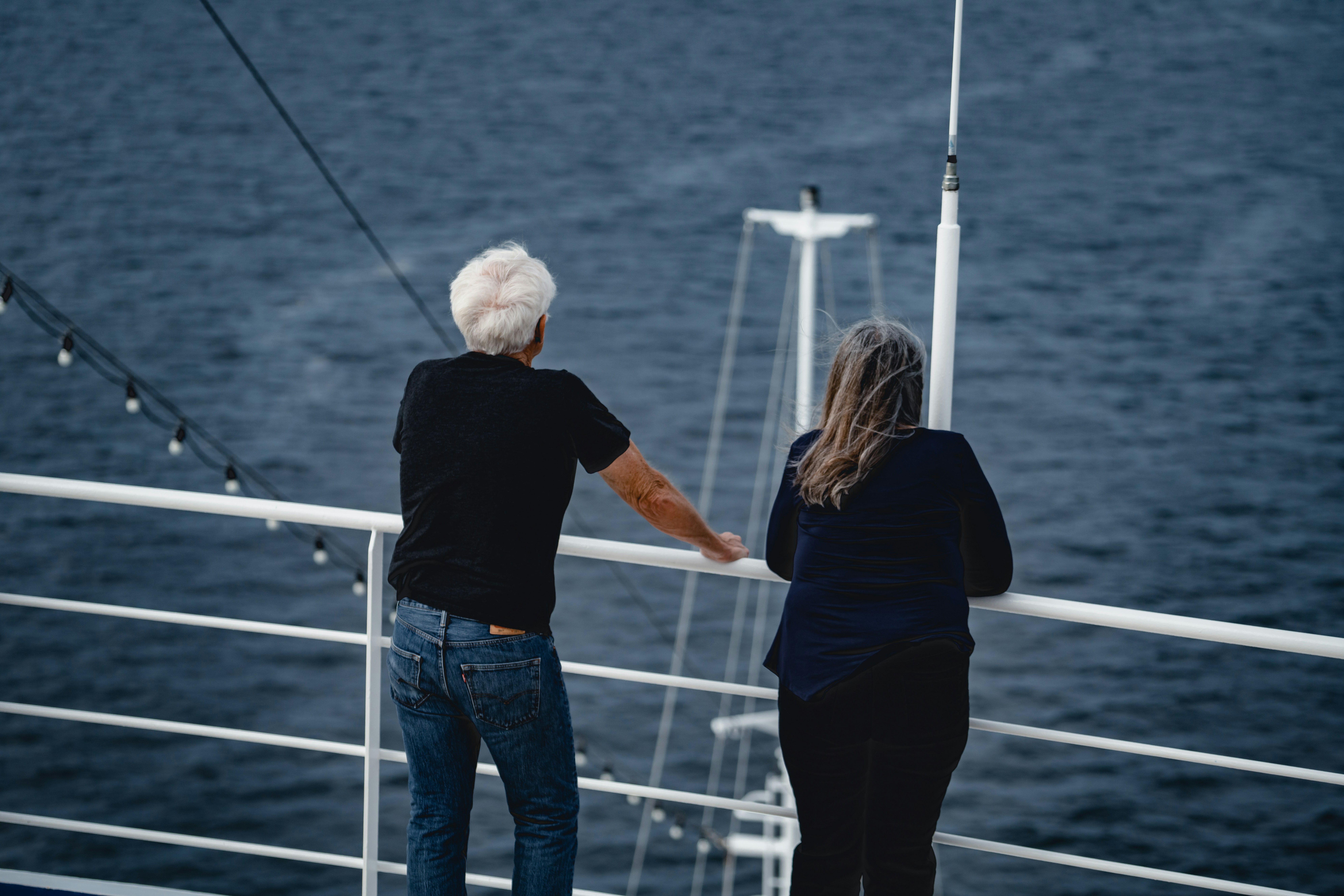 man and woman standing beside rail looking at body of water