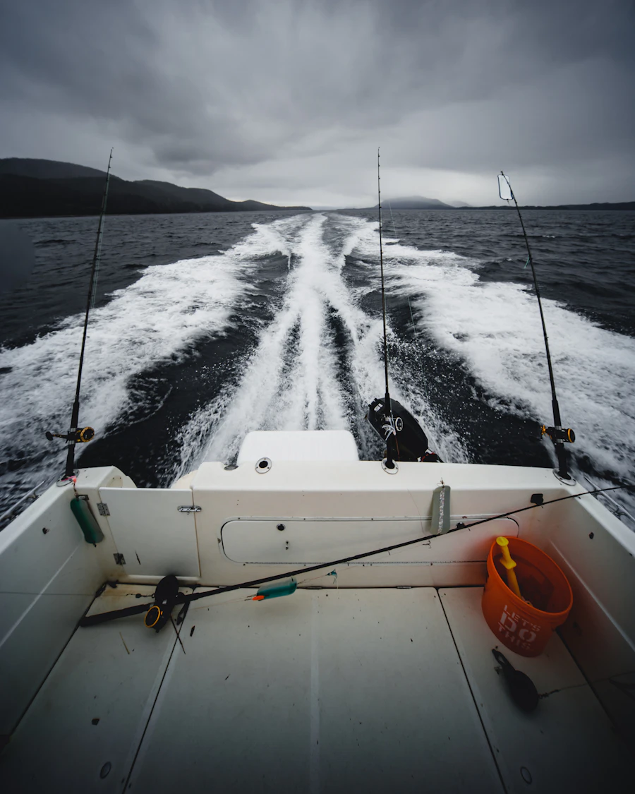 Fishing rods secured on a boat moving out toward open water for a day trip
