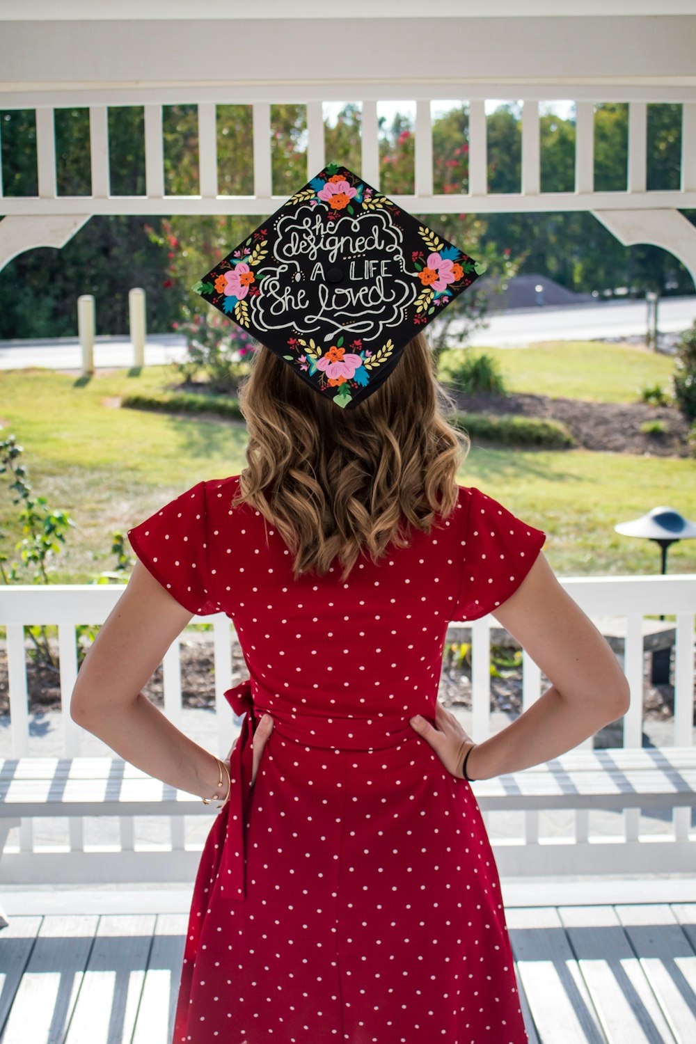 woman wearing red dress and black academic hat facing backward