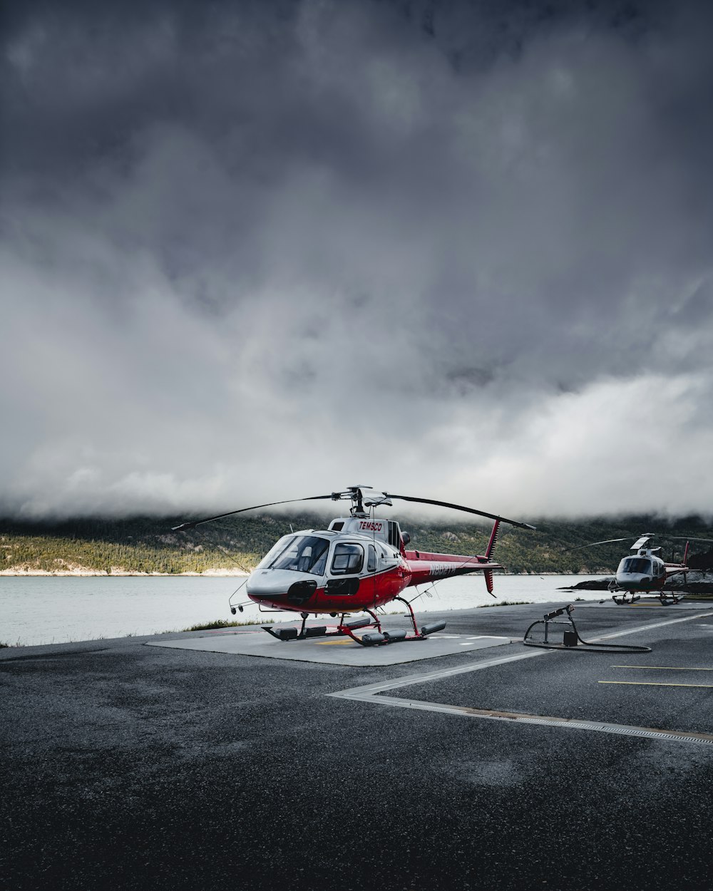 helicopters on paved concrete under white skies