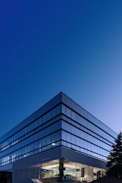 A modern glass office building corner against a clear deep blue sky