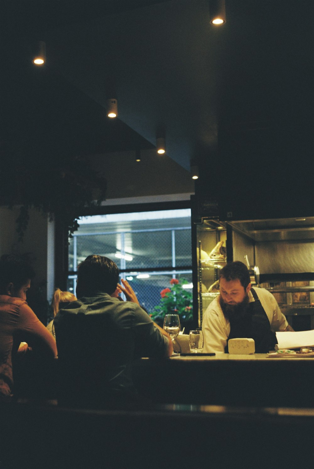 man behind table in apron facing 2 men
