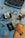 A vintage camera, a typewriter, a passport, and several travel-related items are arranged on an old world map. The collection includes a compass, a bottle with a small ship, a yellow envelope, and dried leaves, evoking a sense of nostalgia and adventure.