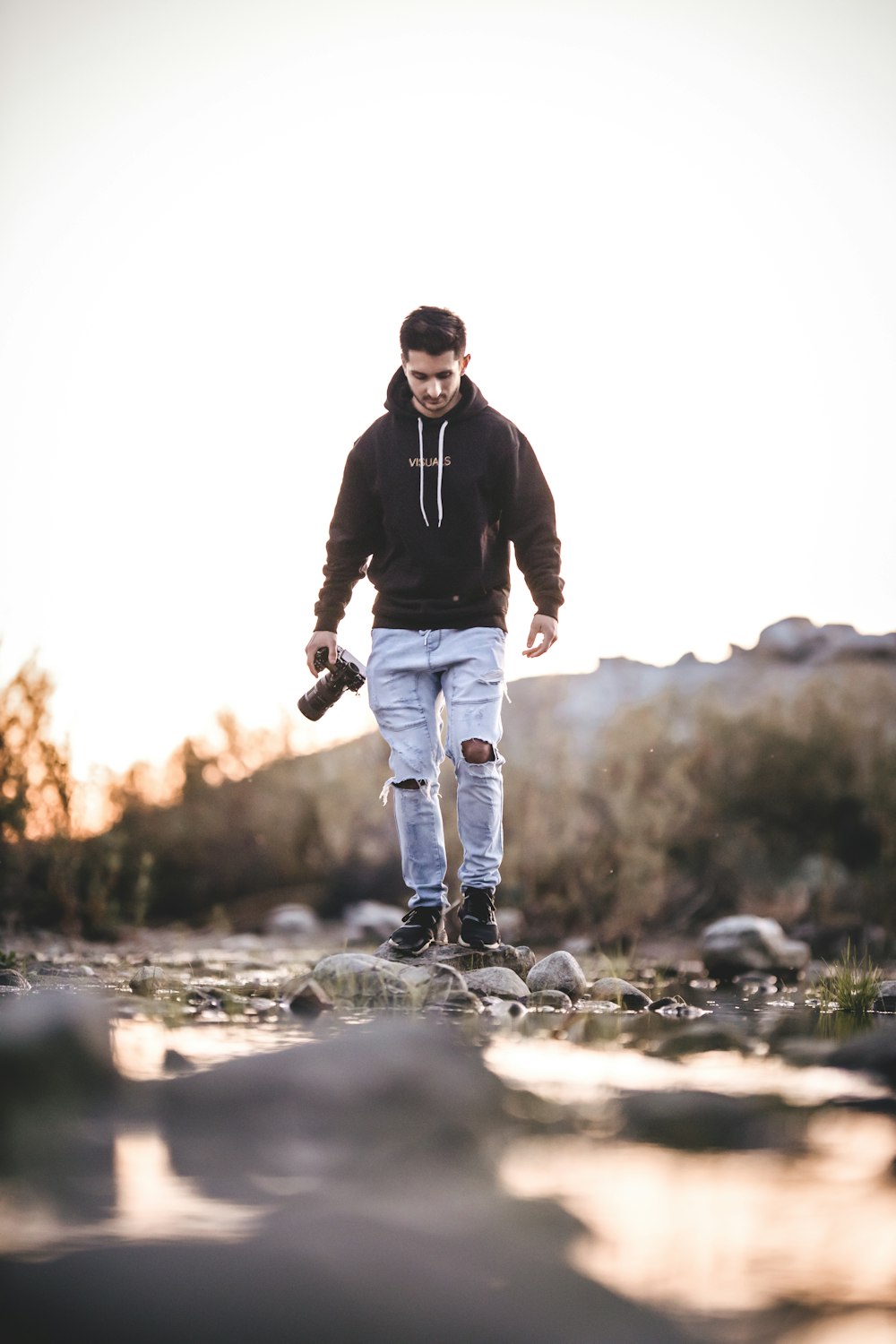 selective focus photography of walking man holding camera during daytime