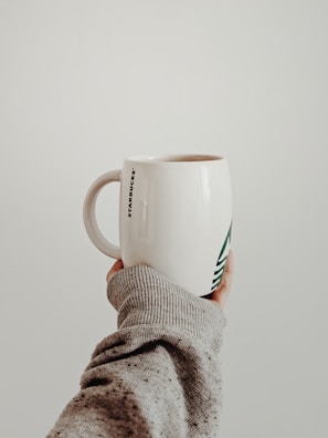 A close-up of a hand holding a mug with a playful, custom logo design.