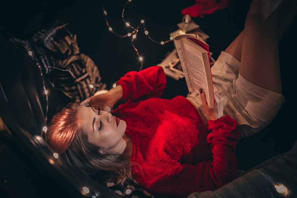 a woman in a red sweater reading a book