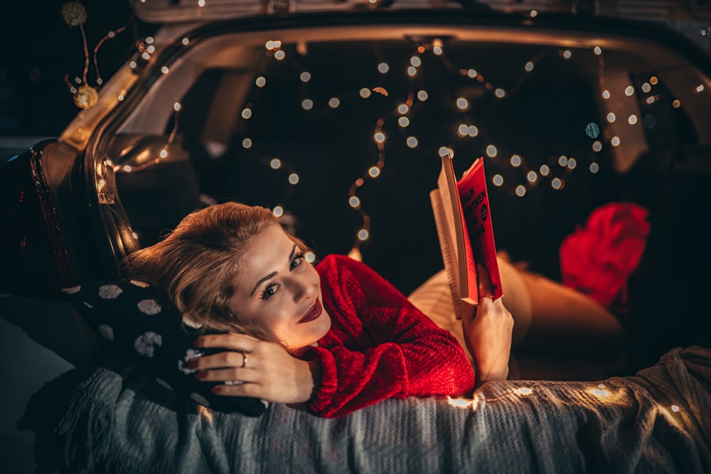 woman lying on bed while reading book