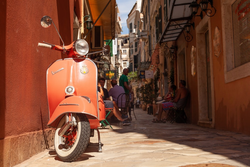 orangefarbener Vespa-Roller neben Haus geparkt