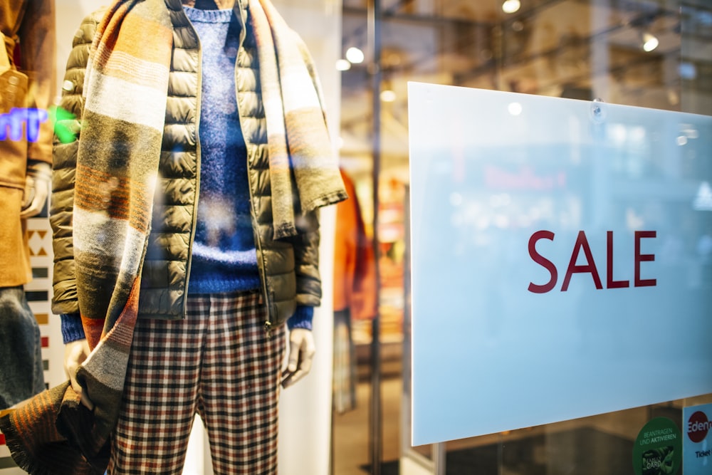 a mannequin in a window display with a sale sign