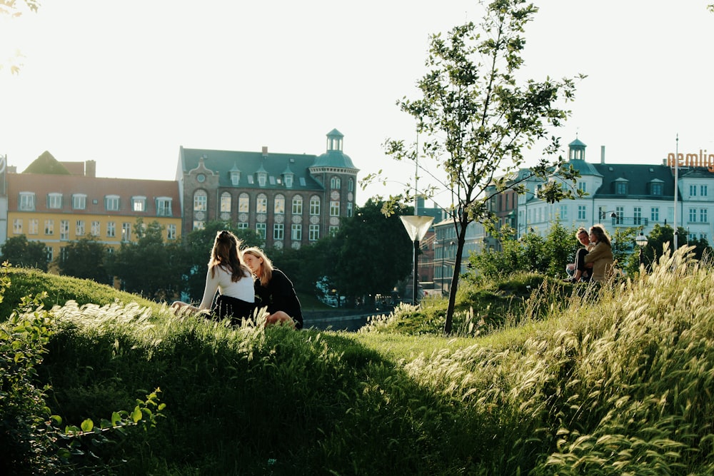 two women sitting on green grass