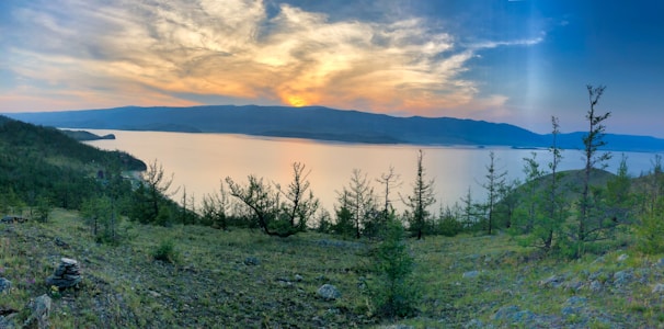 A serene landscape artwork depicting a calm lake at sunset