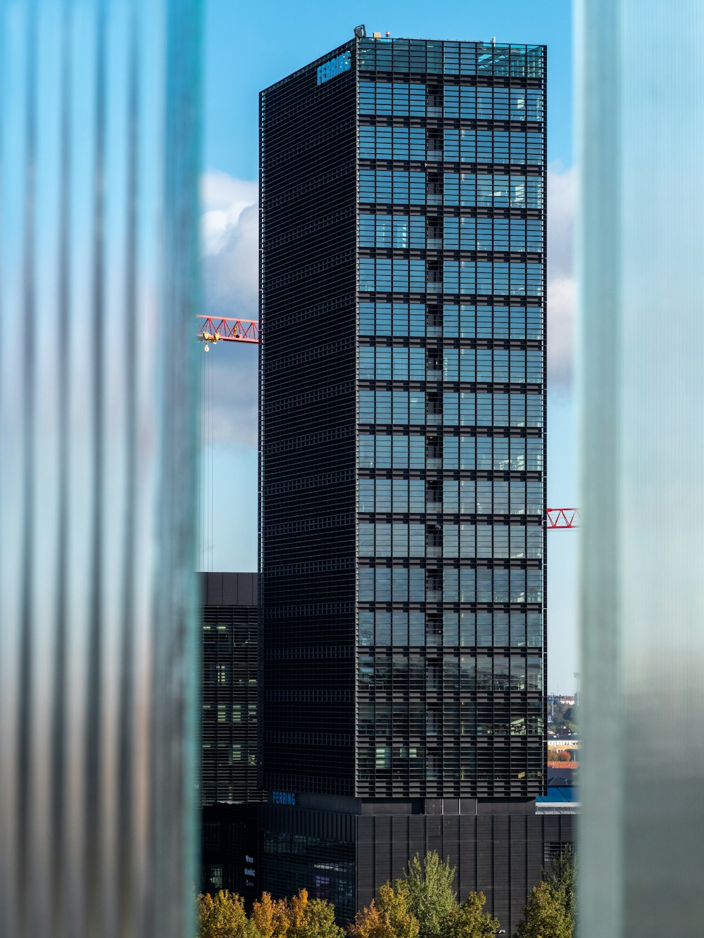 a tall black building with a crane in the background