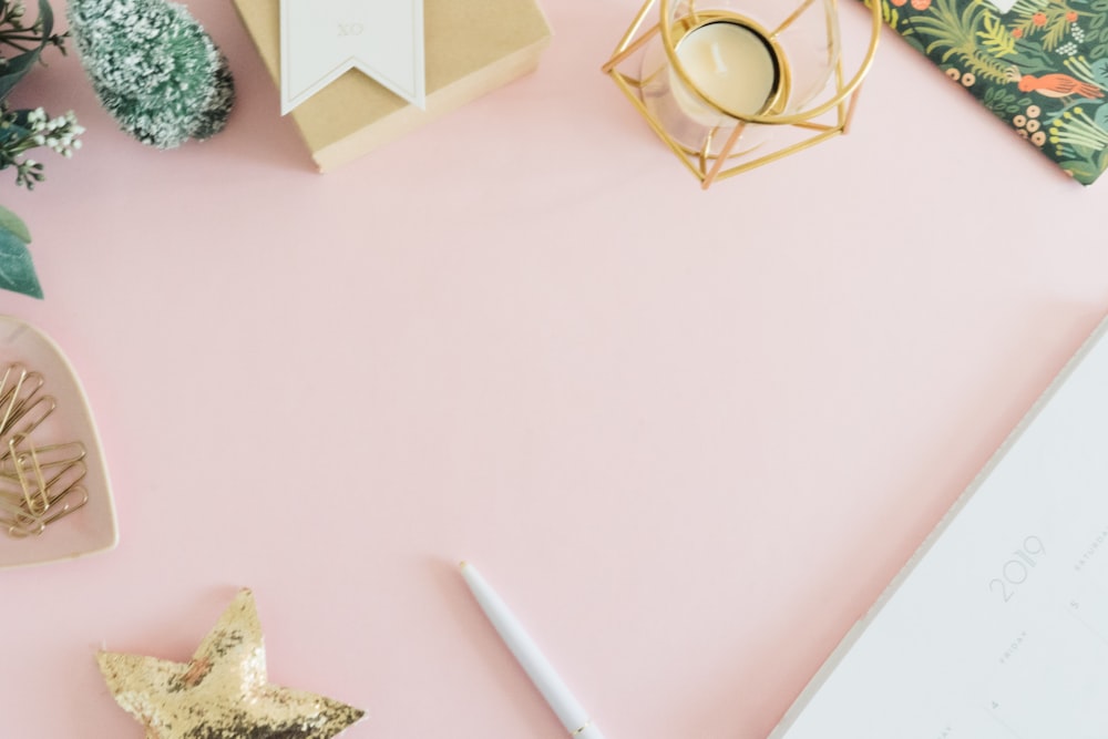 a pink desk with a pen, notebook and other items