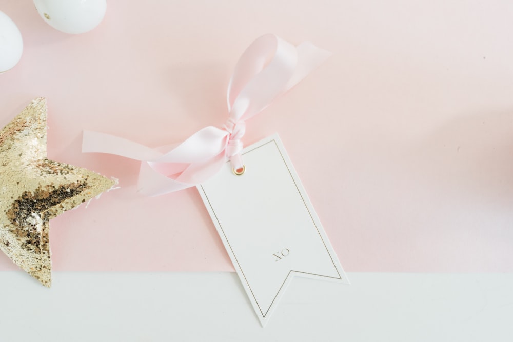 uma decoração de estrela rosa e dourada com uma etiqueta branca