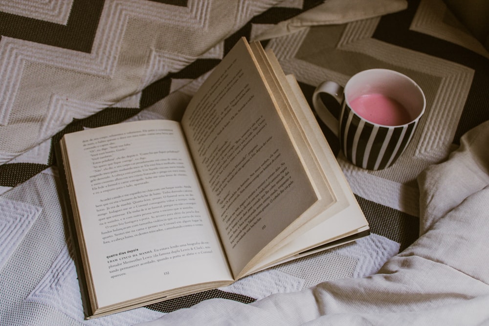 libro bianco aperto accanto a tazza in ceramica bianca e nera