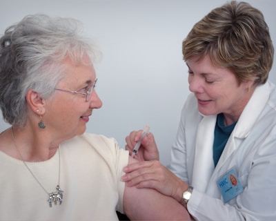 woman inject a woman on left shoulder